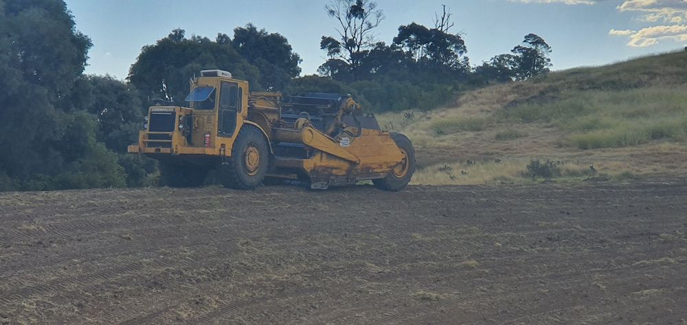 A Yellow Bulldozer is Sitting on Top of a Dirt Field — Oakleigh Earthmoving in Chinchilla, QLD