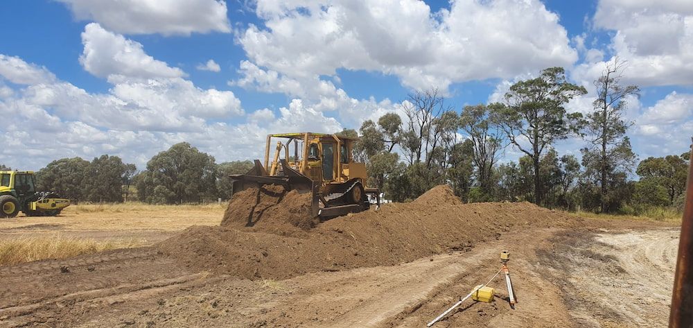 A Bulldozer is Moving a Pile of Dirt in a Field — Oakleigh Earthmoving in Chinchilla, QLD