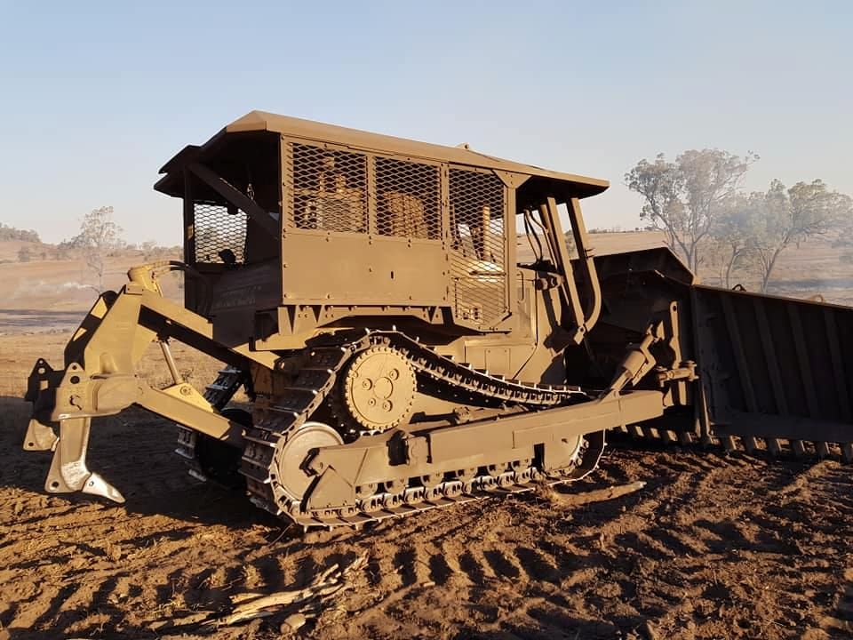 An Old Bulldozer is Sitting in a Dirt Field — Oakleigh Earthmoving in Kingaroy, QLD