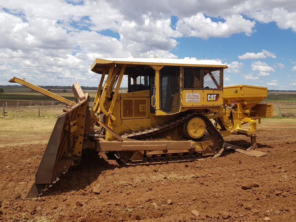 A Yellow Bulldozer is Parked in a Dirt Field — Oakleigh Earthmoving in Moonie, QLD