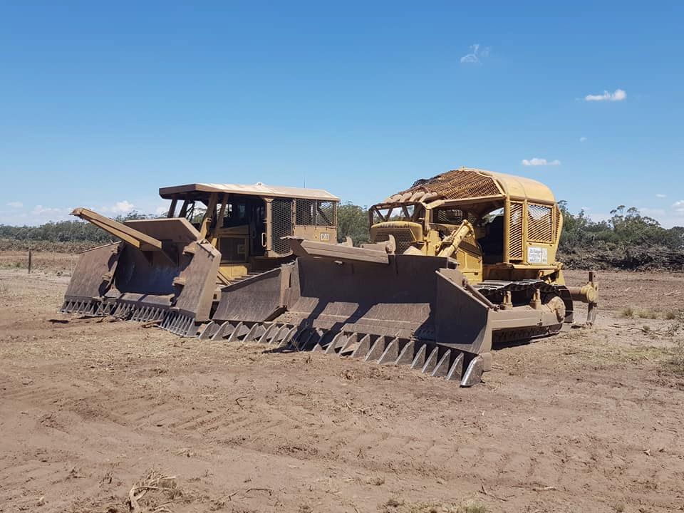 Two Bulldozers Are Parked Next to Each Other in a Dirt Field — Oakleigh Earthmoving in Moonie, QLD