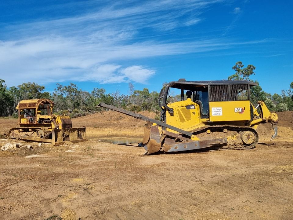 Yellow Construction Equipment on a Dirt Site Under a Blue Sky — Oakleigh Earthmoving in Cotswold Hills, QLD