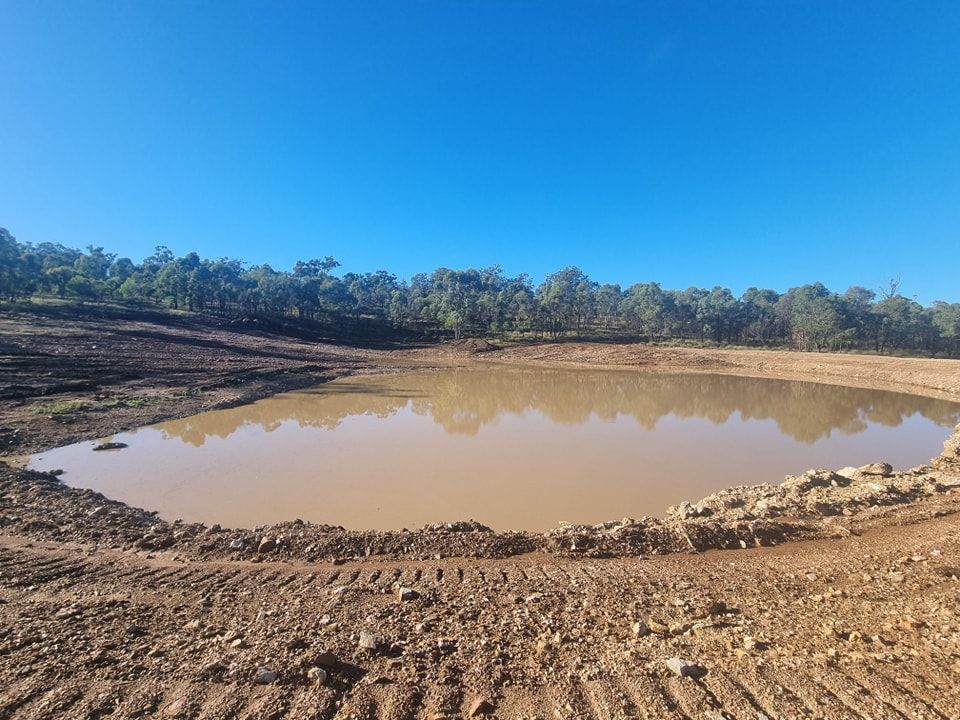 Mud-filled Excavation Pond Under a Blue Sky, Surrounded by Dirt and Trees — Oakleigh Earthmoving in Cotswold Hills, QLD