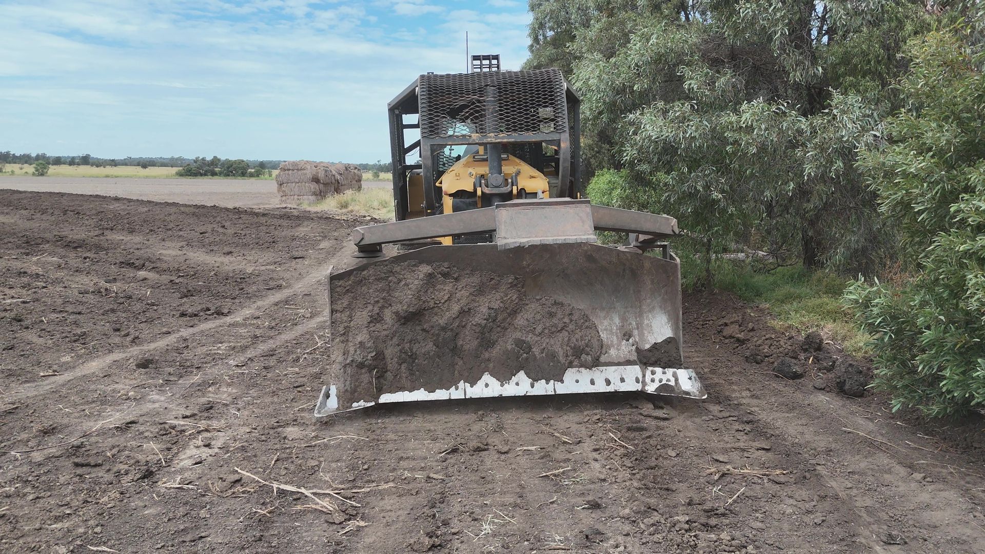 Bulldozer Pushing Dirt on a Rural Construction Site With Trees in the Background — Oakleigh Earthmoving in Warwick, QLD