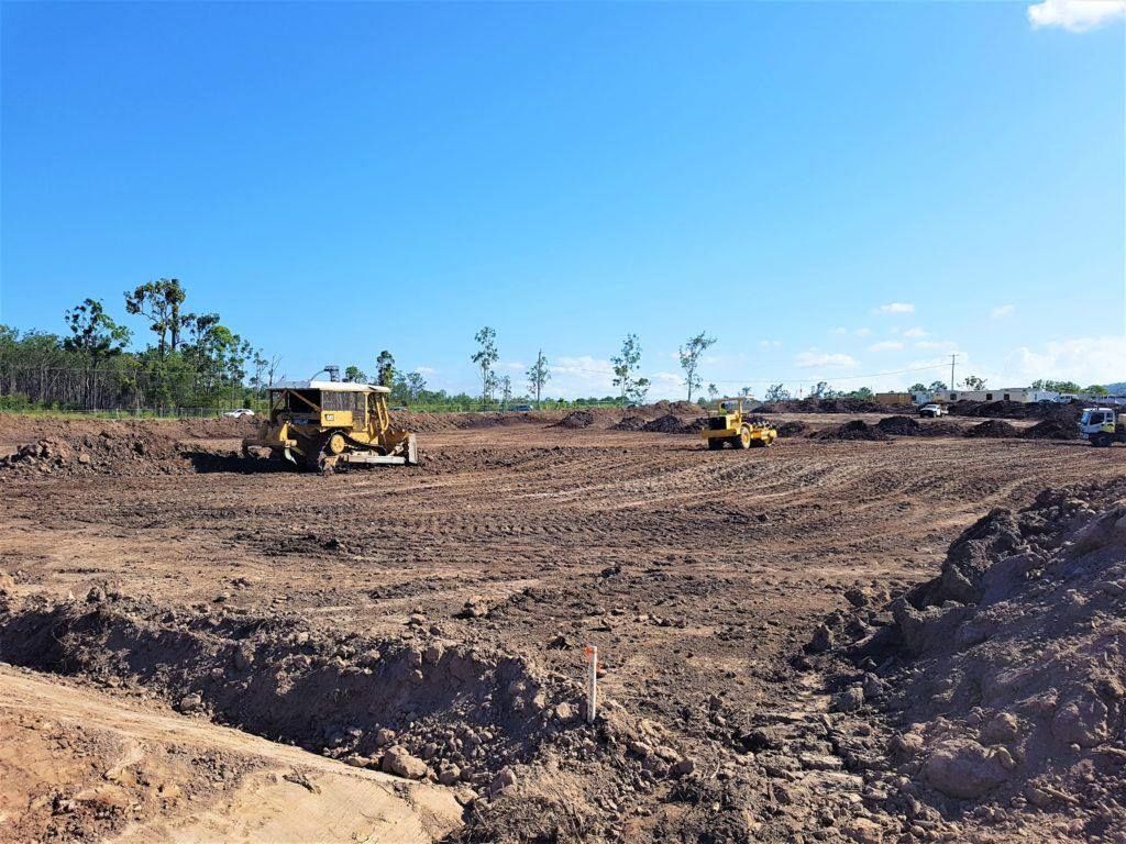Bulldozers Grading a Large Dirt Lot Under a Clear Blue Sky, With Trees in Distance — Oakleigh Earthmoving in Chinchilla, QLD