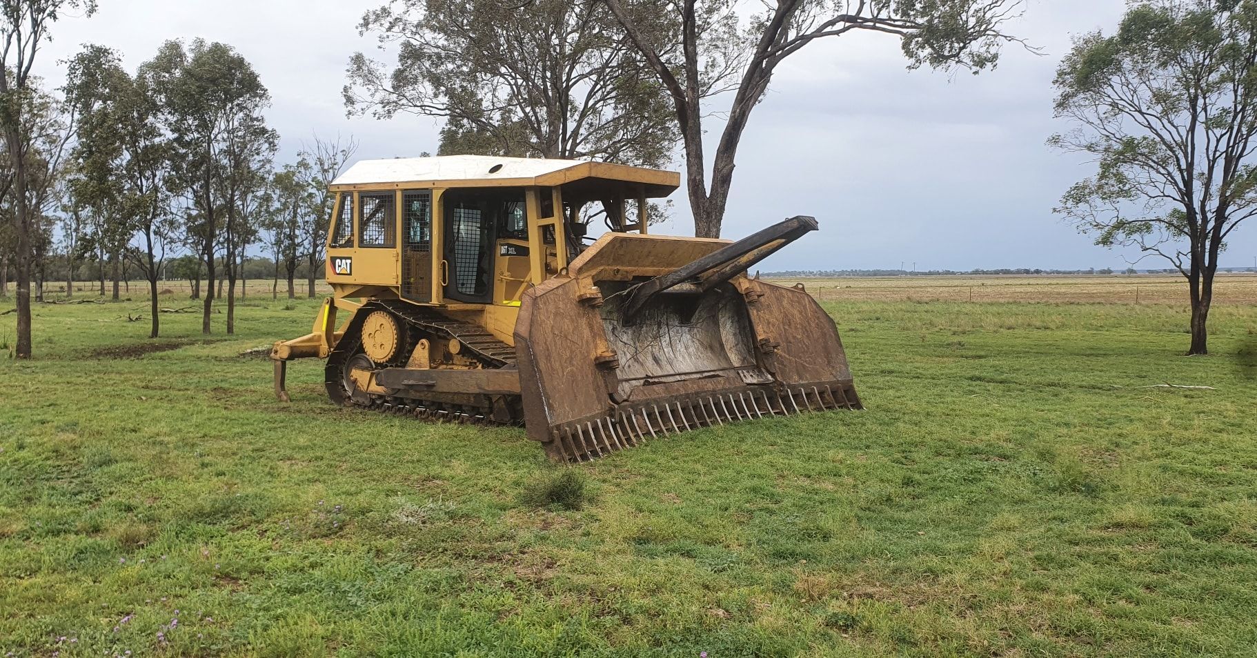 A Large Excavator is Driving Through a Dirt Field — Oakleigh Earthmoving in Dalby, QLD
