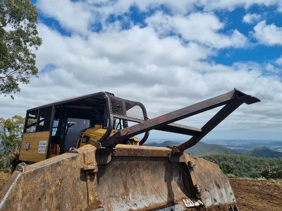 A Bulldozer is Parked on Top of a Dirt Hill — Oakleigh Earthmoving in Cotswold Hills, QLD