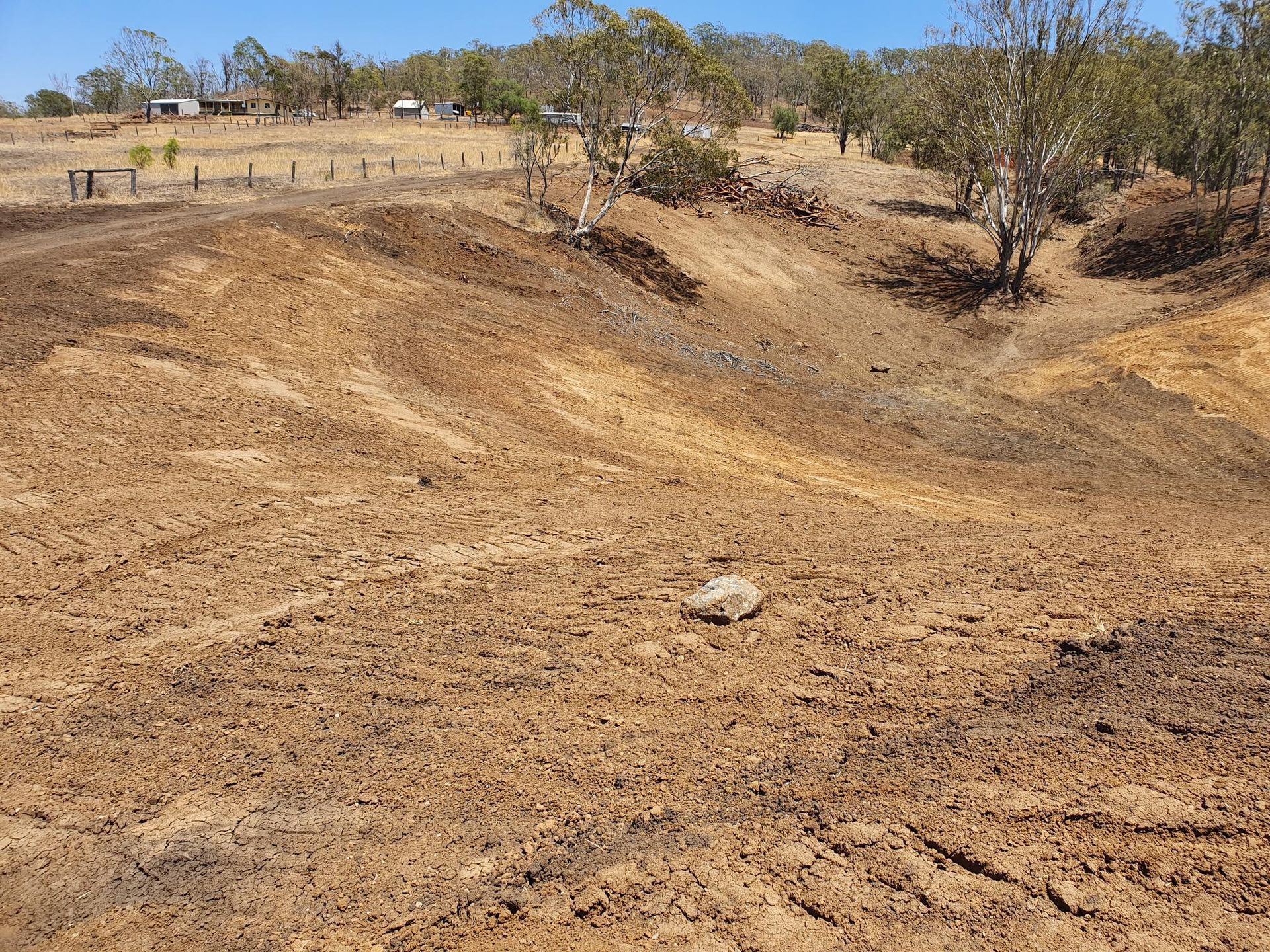Dry, Rocky Dirt Gully With Sparse Trees and Grassy Field in the Background — Oakleigh Earthmoving in Cotswold Hills, QLD