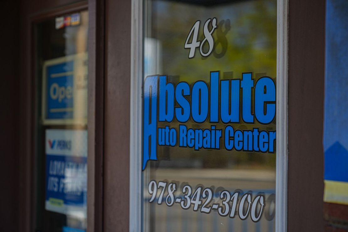 Storefront window with blue “Absolute Auto Repair Center” sign and phone number 978-342-3100