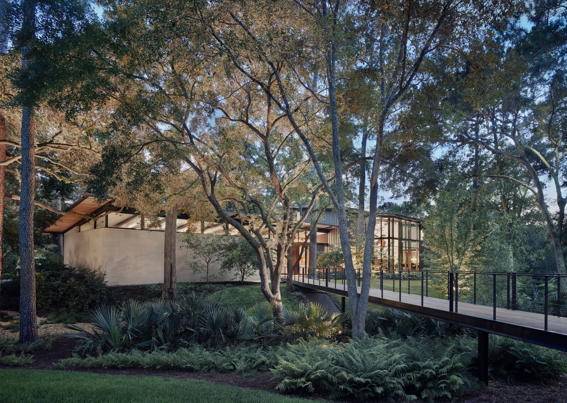 a house with a bridge leading to it is surrounded by trees .
