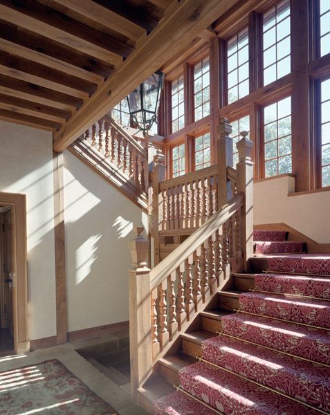 a staircase with a wooden railing and a red carpet