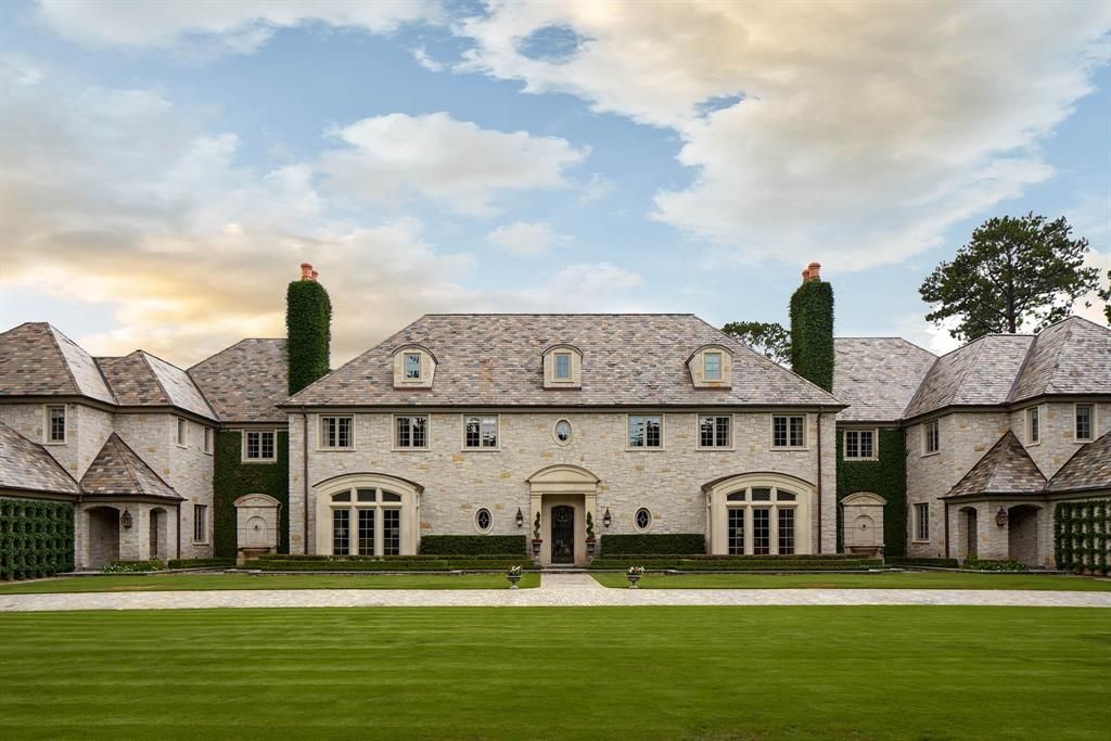 a large house with a lot of windows and chimneys is sitting on top of a lush green field .