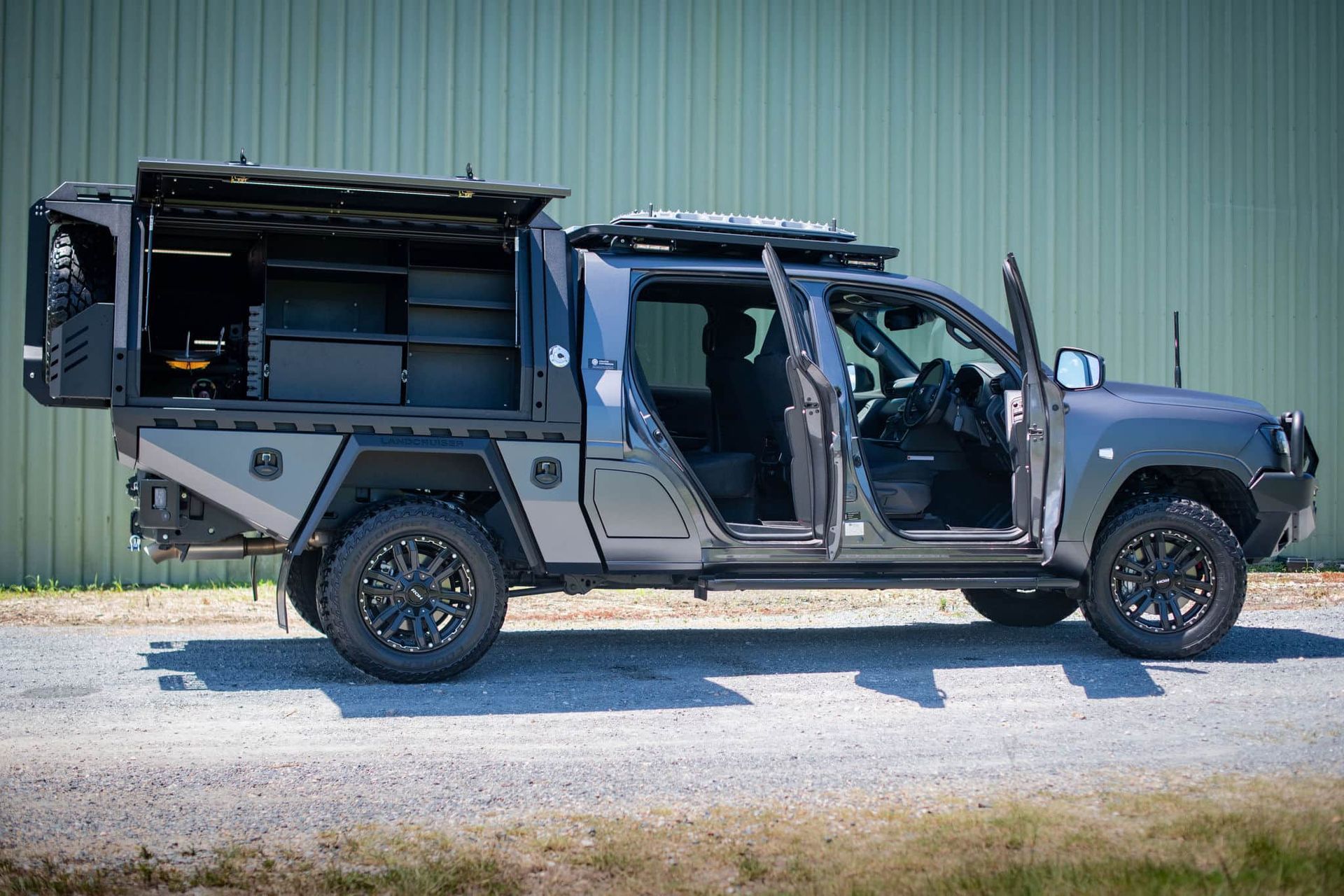 Grey Custom Off-road Truck With Opened Doors and Storage Compartments, Parked Against a Green Wall — Custom RV Creations in Gold Coast, QLD