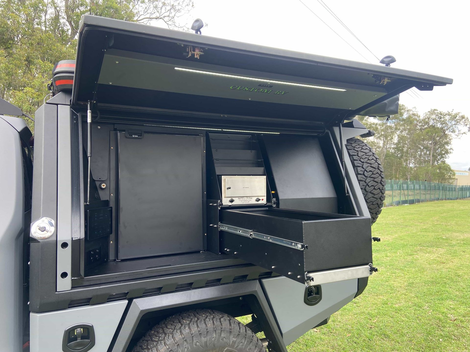 Grey Truck Bed With Open Canopy Revealing a Refrigerator, Drawer, and Storage Compartments — Custom RV Creations in Sumner, QLD