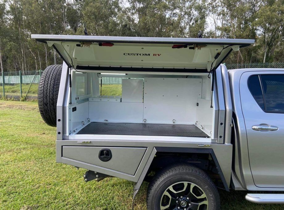 A Silver Vehicle With the Canopy Open is Parked in a Grassy Field — Custom RV Creations in Sumner, QLD