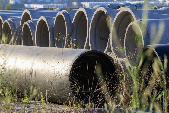 Stacked concrete drainage pipes outdoors, with one large pipe in the foreground