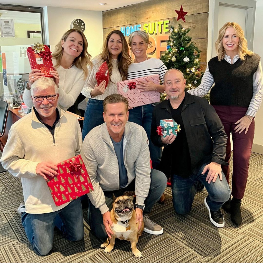 A group of people are posing for a picture with a dog in front of a christmas tree.