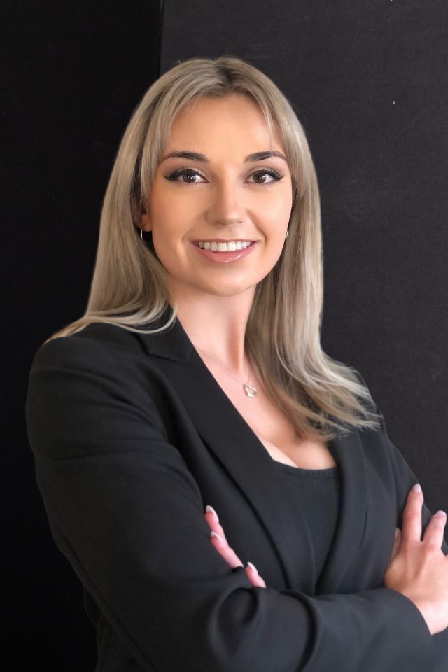 A woman in a black suit is posing for a picture with her arms crossed.