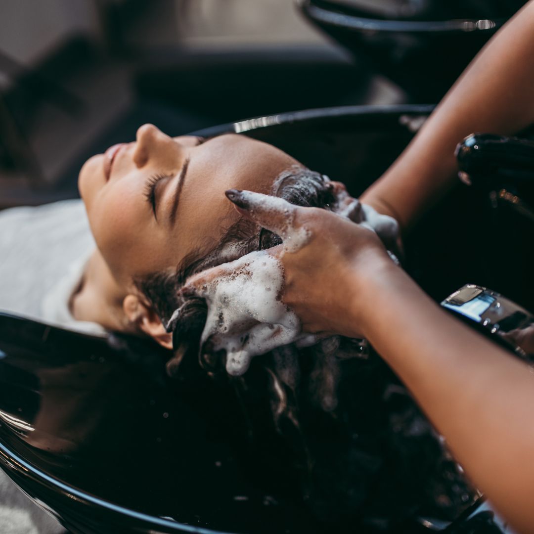 A woman is getting her hair washed in a sink at a salon.
