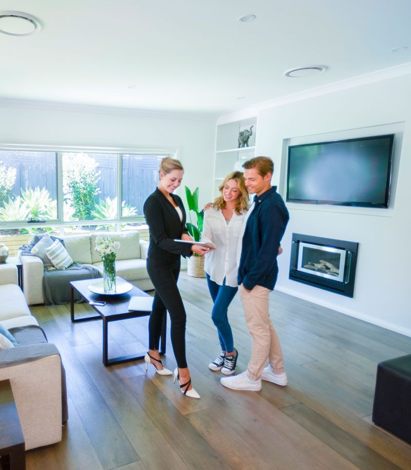 A realtor is talking to a man and a woman in a living room.