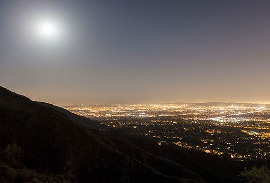 A full moon is shining over a city at night.