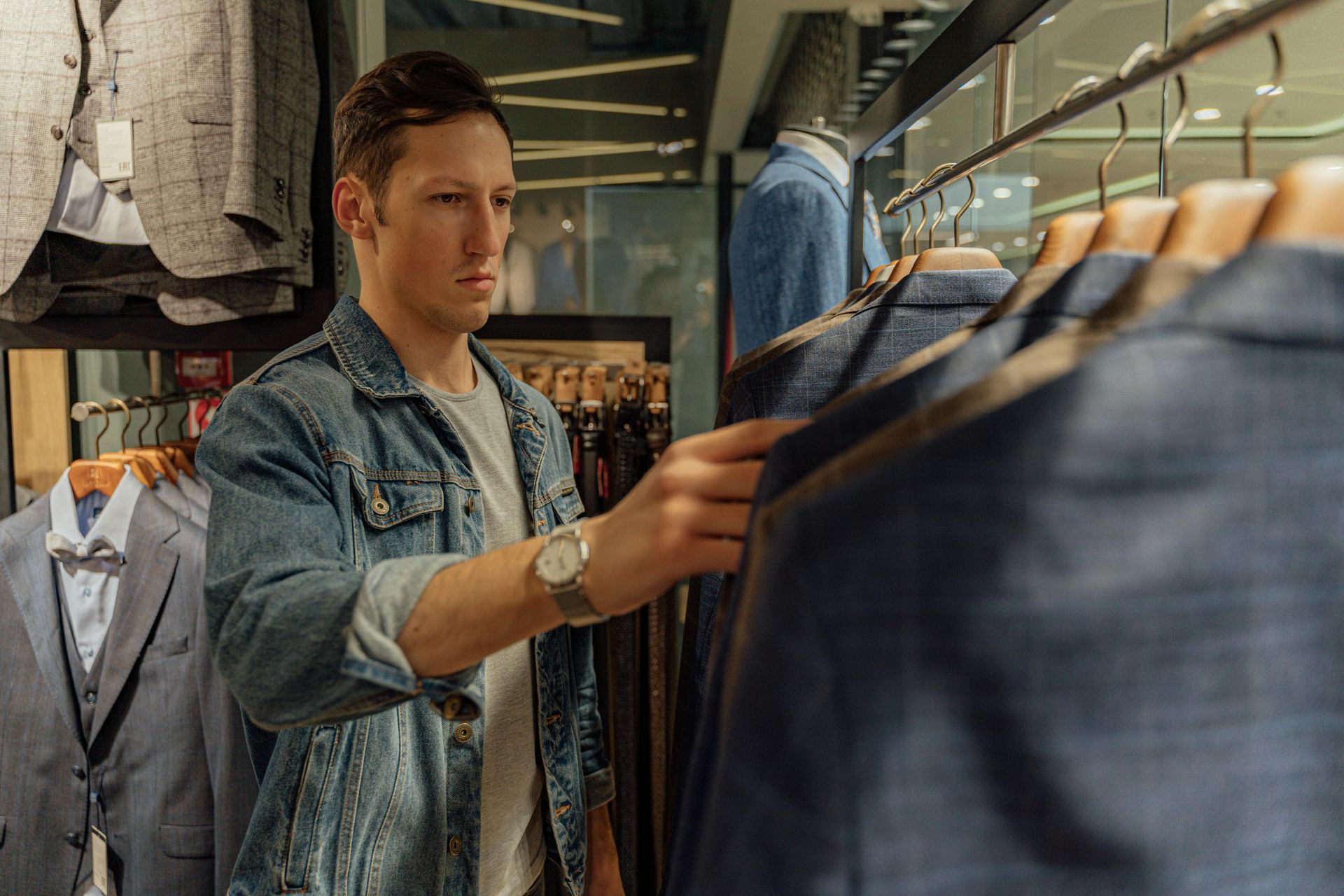 A man is looking at a jacket in a clothing store.