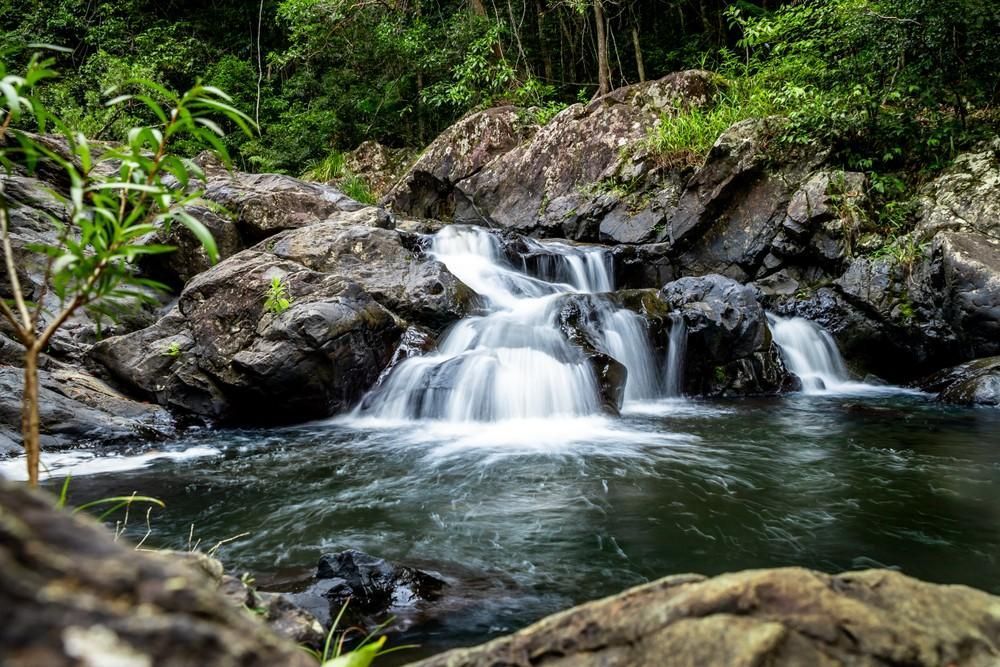 Small Waterfall Cascading Over Dark Rocks Into a Pool — Gordon's Air Conditioning & Refrigeration Services in Kenilworth, QLD