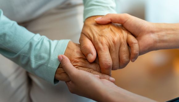 Two hands holding each other; one older, one younger, symbolizing care and support.