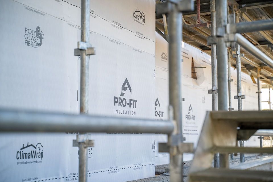 Construction site with scaffolding and white building wrap with logos.