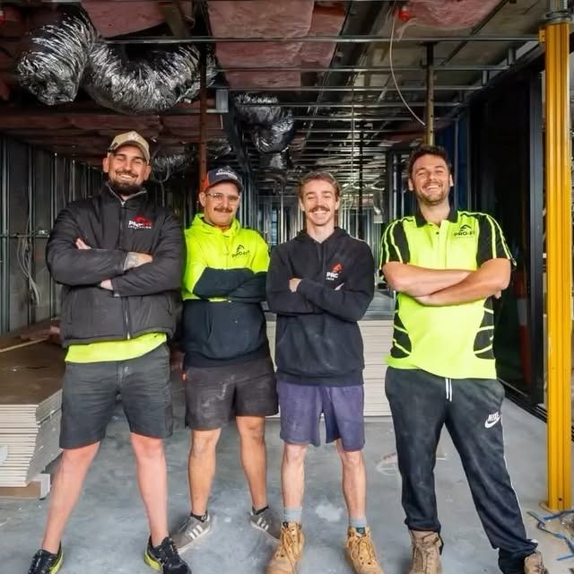 Four construction workers posing in a building under construction.