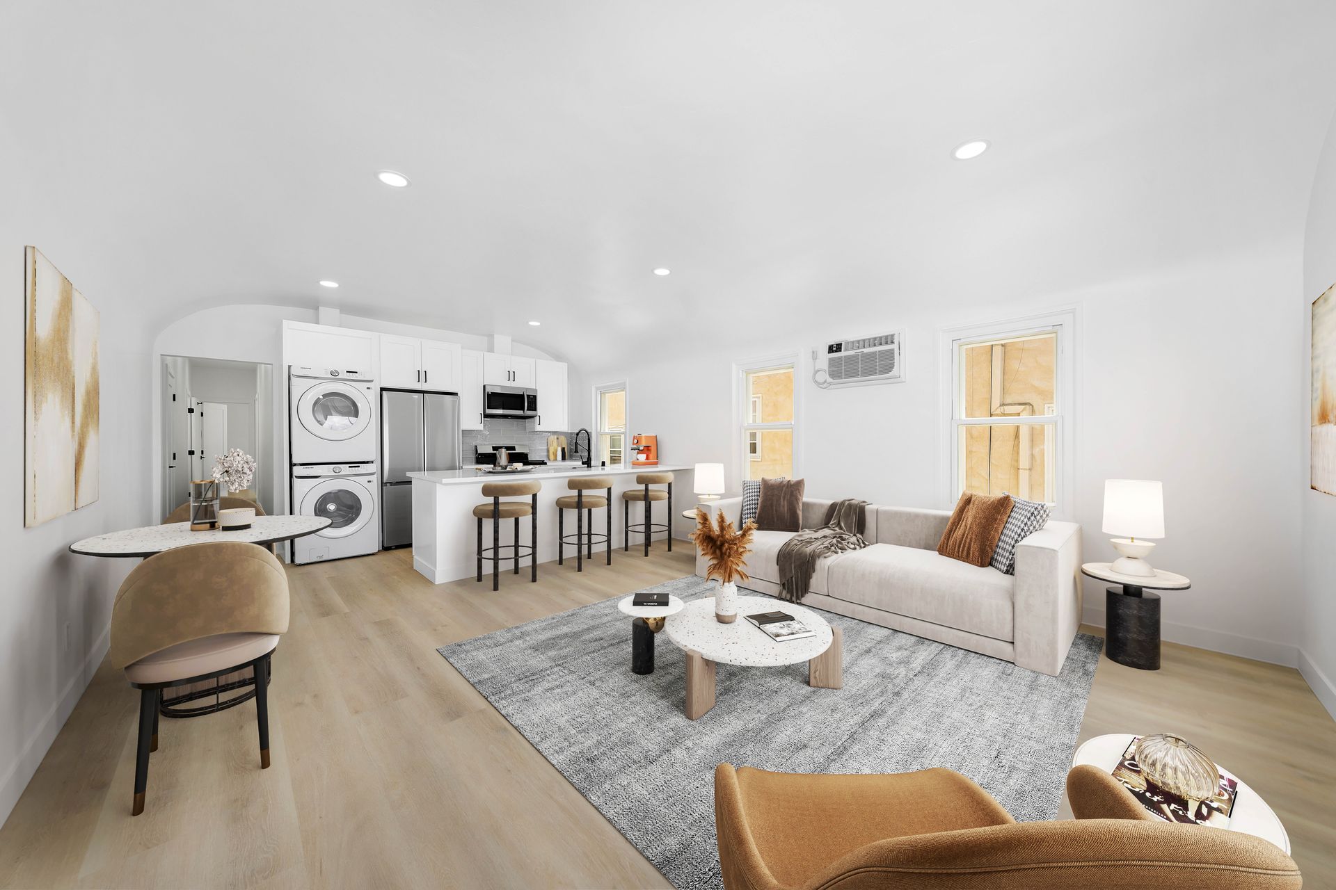 A living room with a couch , chairs , a coffee table and a kitchen.