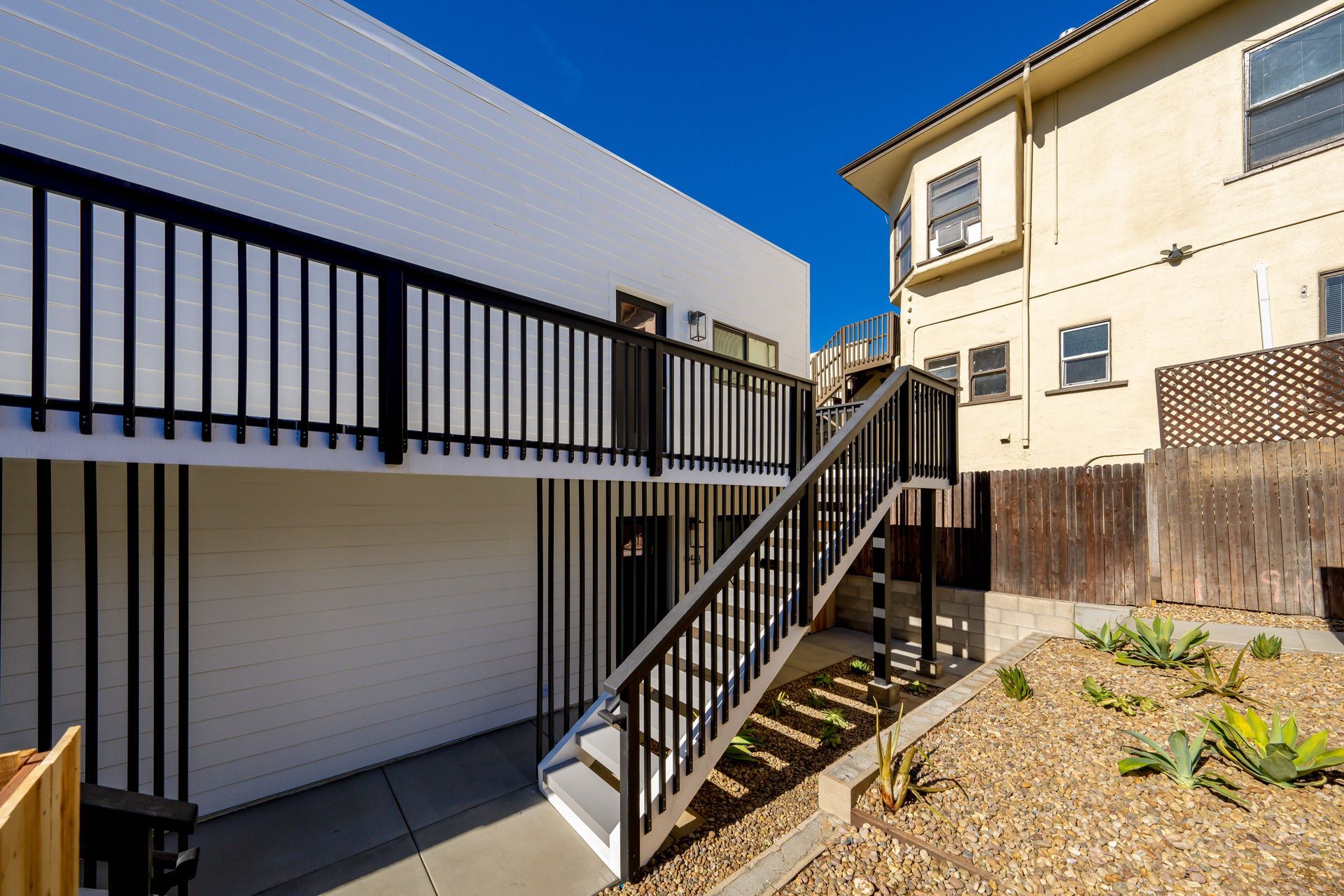 A white building with a black railing and stairs leading up to it.