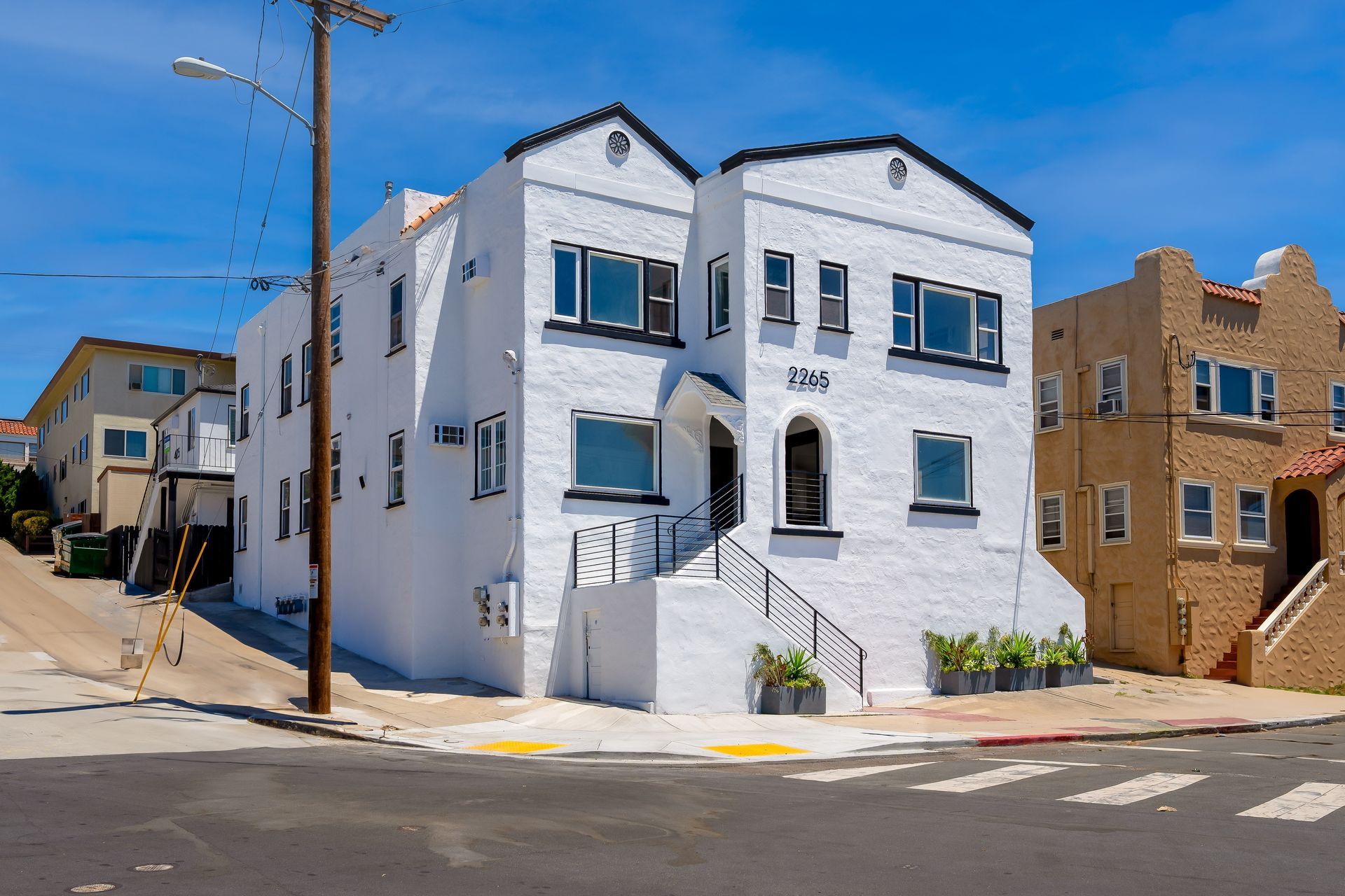 A white apartment building is sitting on the corner of a street.