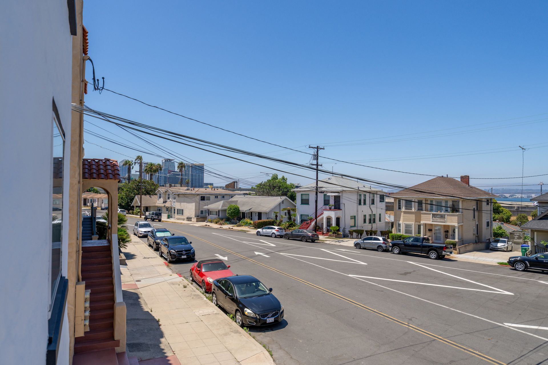 A row of cars are parked on the side of a city street.