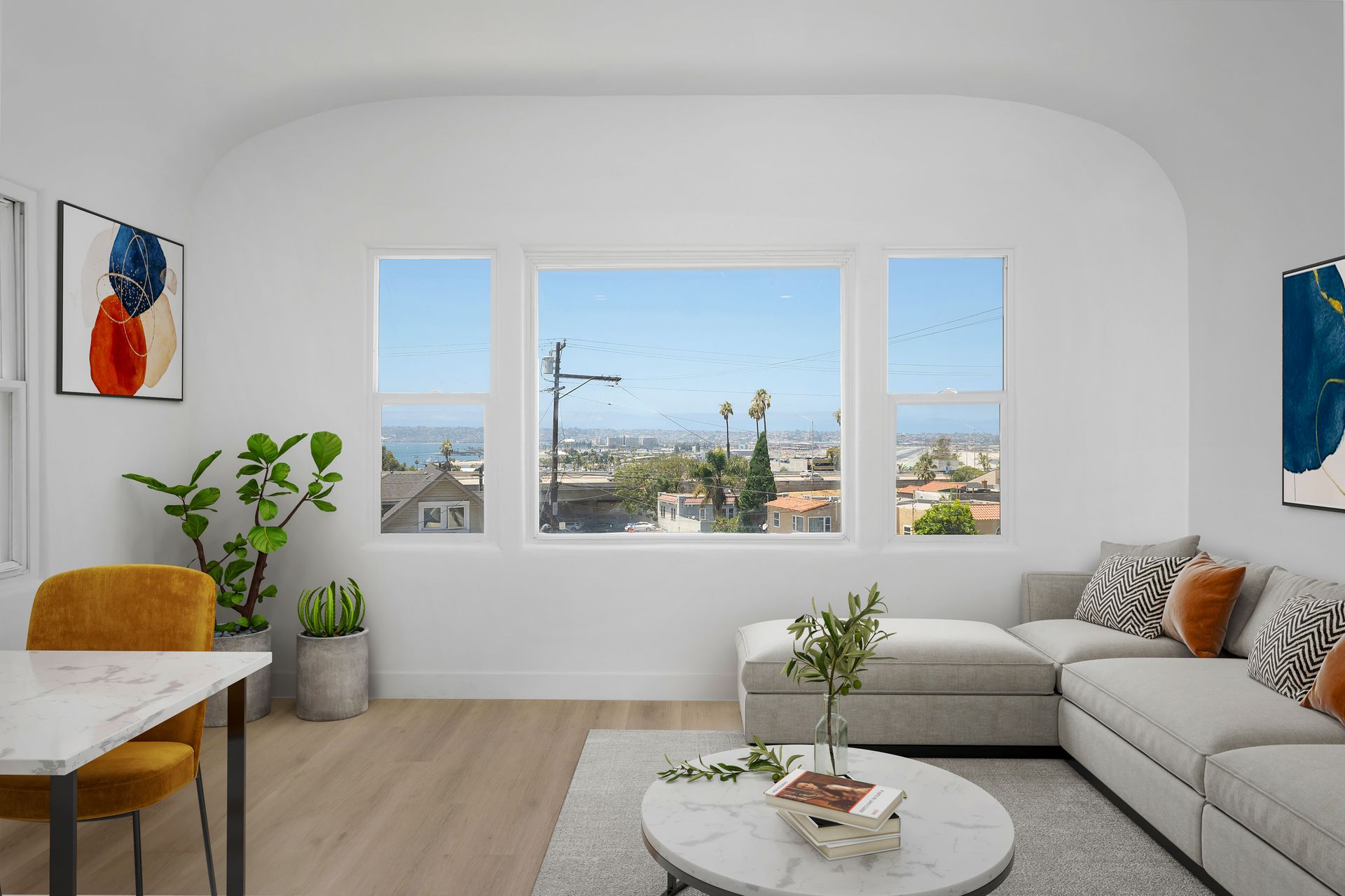 A living room with a couch , table , chairs and a large window.