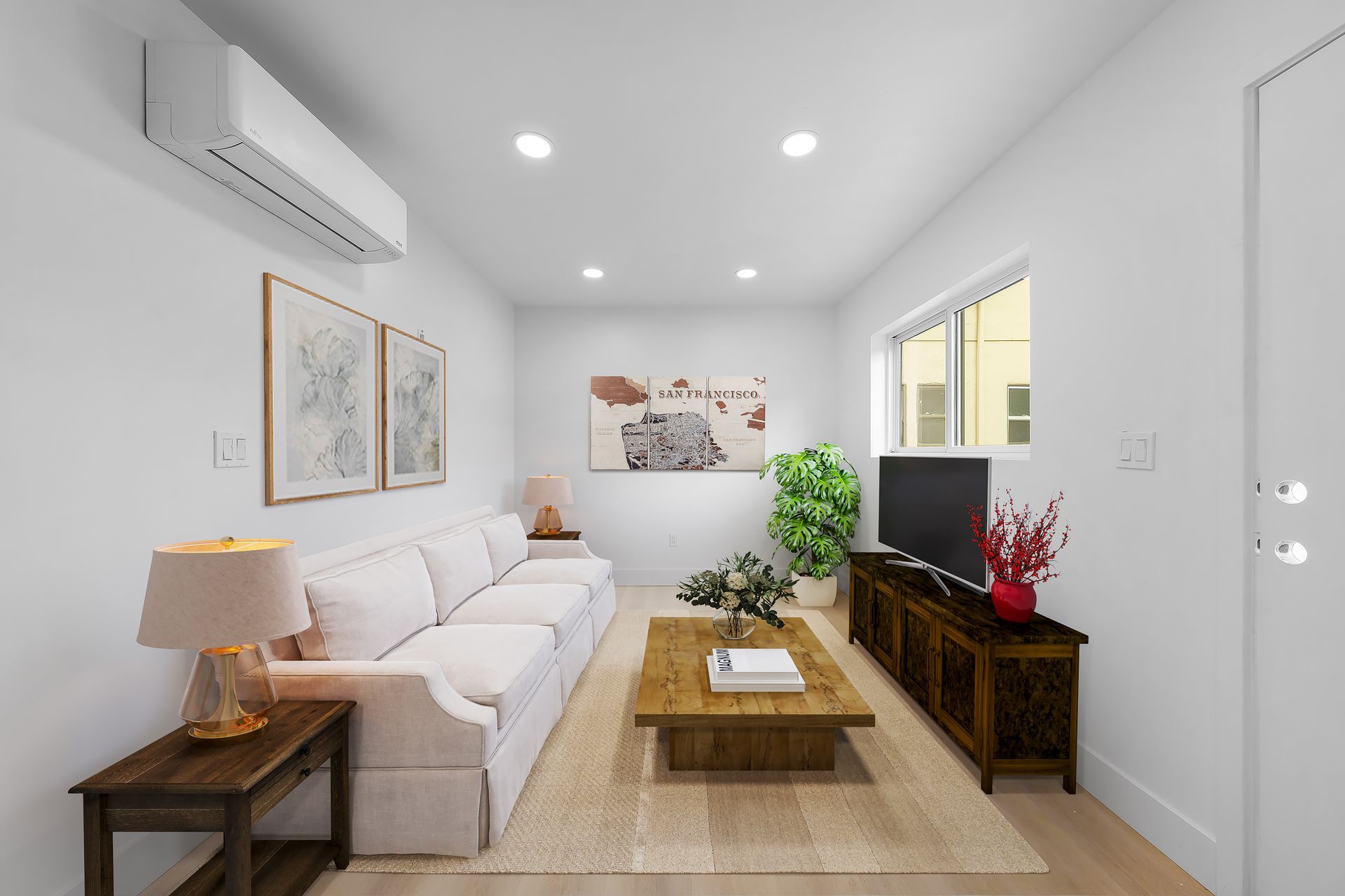 A living room with a couch , coffee table , television and air conditioner.