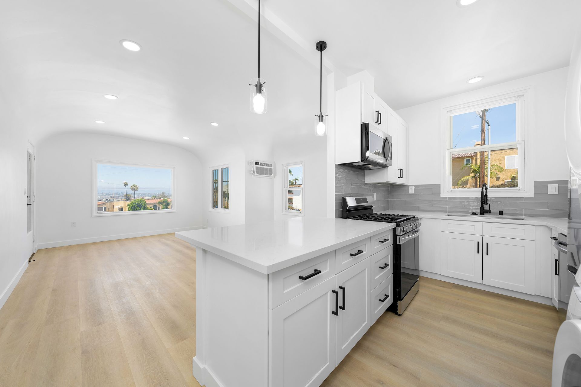 A kitchen with white cabinets , stainless steel appliances , and hardwood floors.
