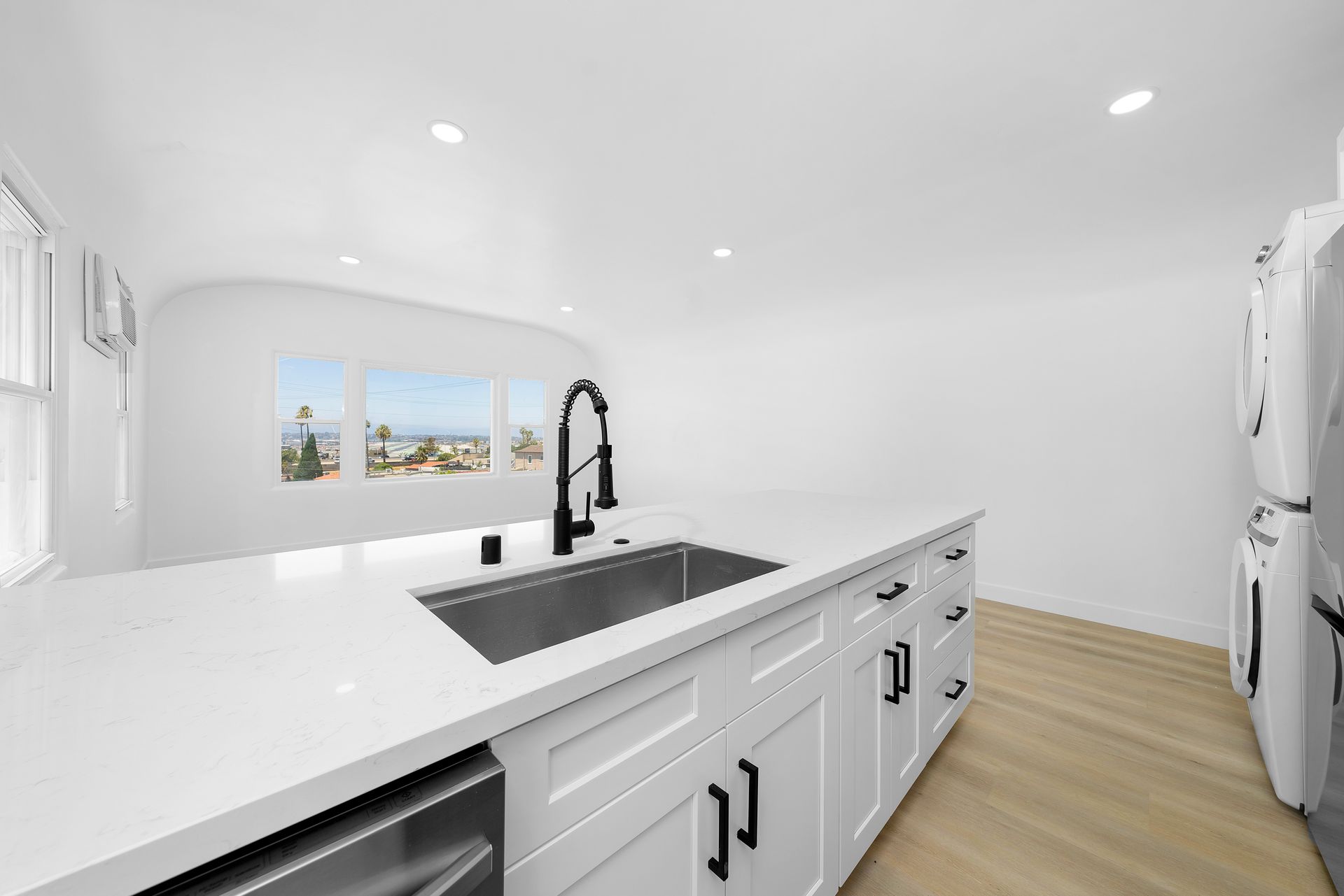A kitchen with white cabinets , a sink , and a refrigerator.