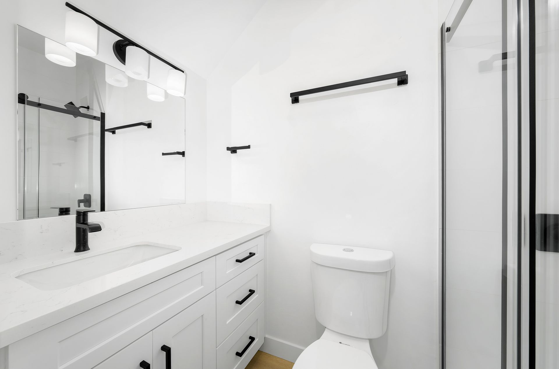 A bathroom with a toilet , sink , mirror and shower.