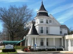 White Victorian house with turret and wraparound porch under a blue sky