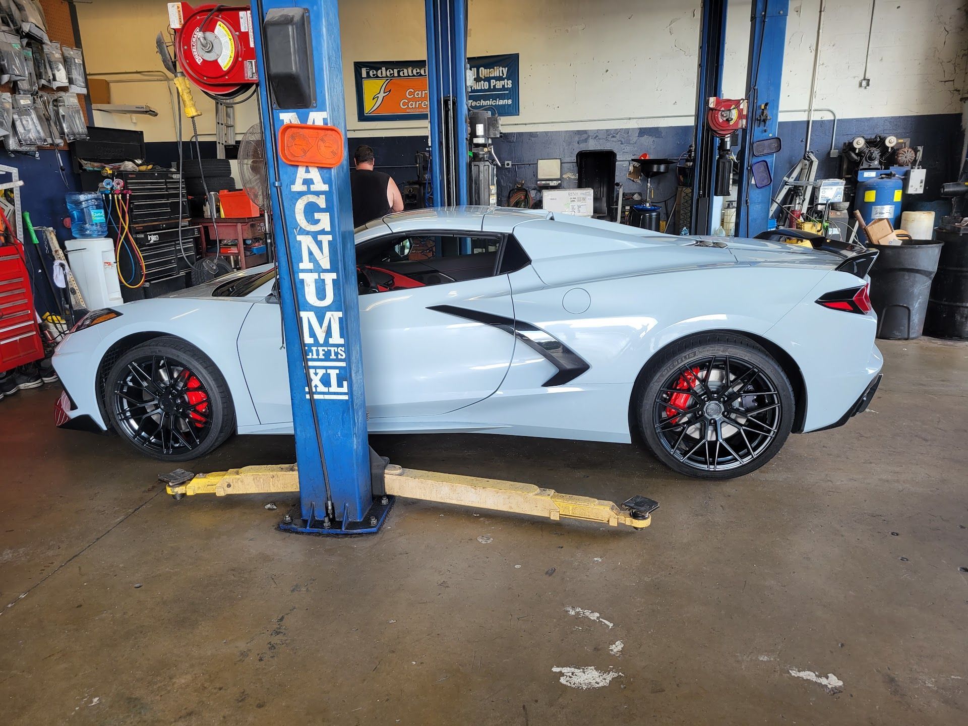 Light blue Corvette on a lift in a garage | St. Lucie Auto Dynamics