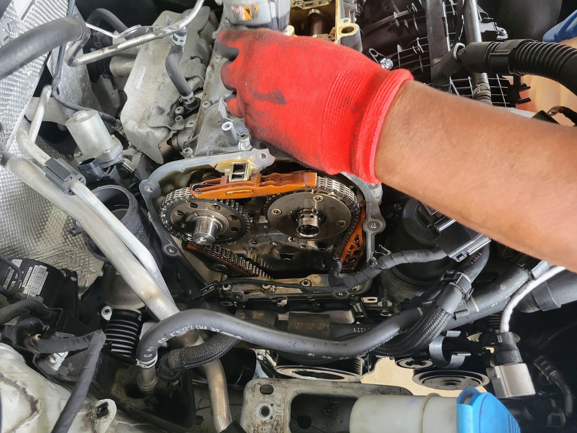 A mechanic wearing a red glove works on a car engine | St. Lucie Auto Dynamics