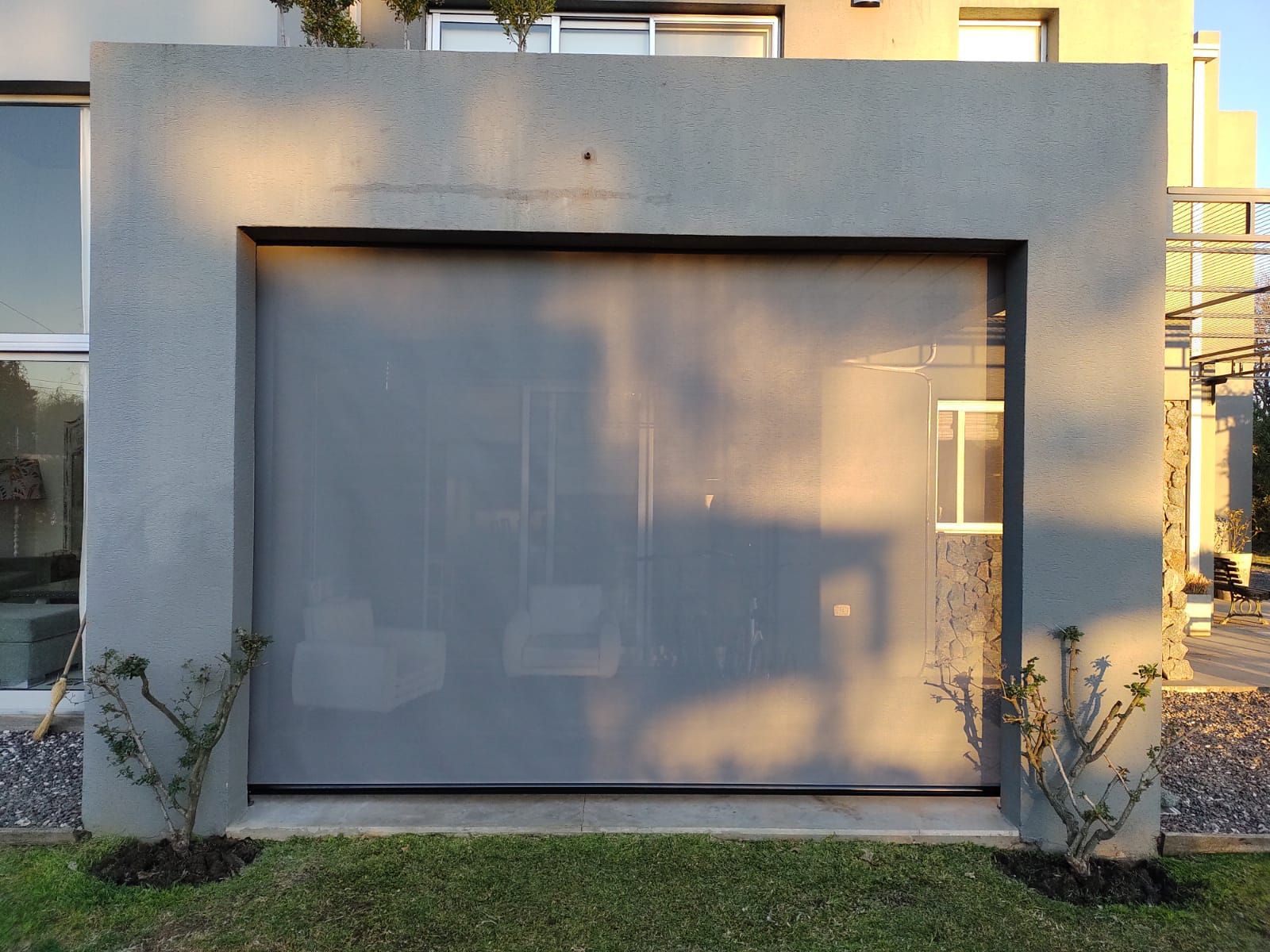 Pequeño local comercial moderno con una gran ventana esmerilada y fachada gris bañada por la cálida luz del sol.