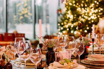 A table set for a christmas dinner with a christmas tree in the background.