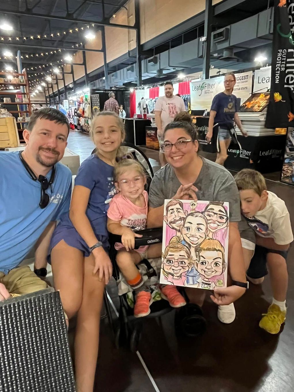 Family seated indoors at a restaurant, smiling and posing with a colorful menu sign.