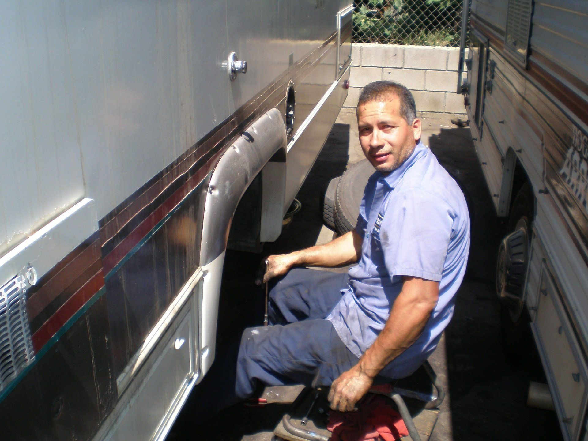 A man in a blue shirt is sitting on a stool next to a trailer