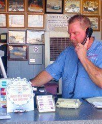 A man is sitting at a counter talking on a cell phone.