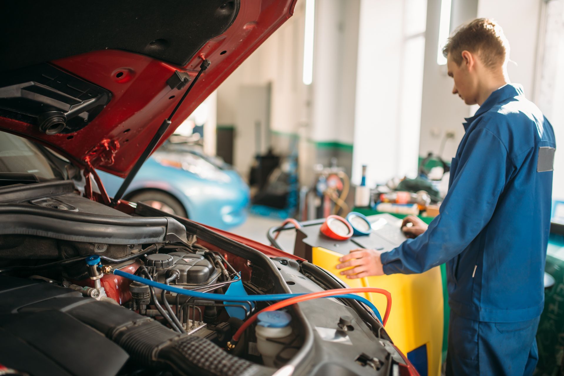 Mechanic pumps freon into a conditioning system.