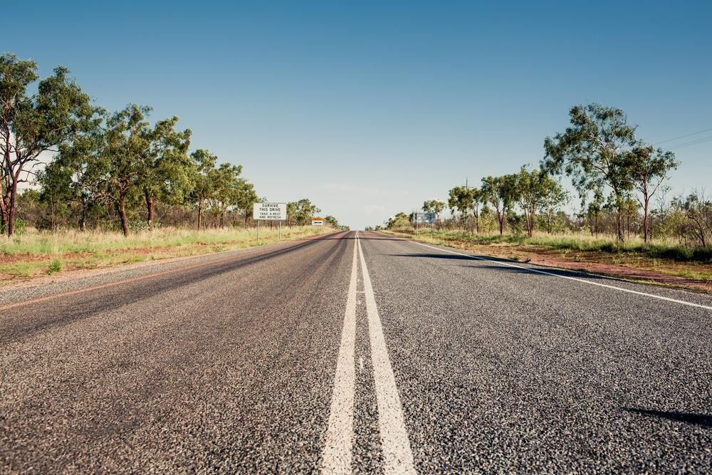 An empty highway with trees on both sides and a blue sky in the background — Active Tree Fellas in Torbanlea, QLD