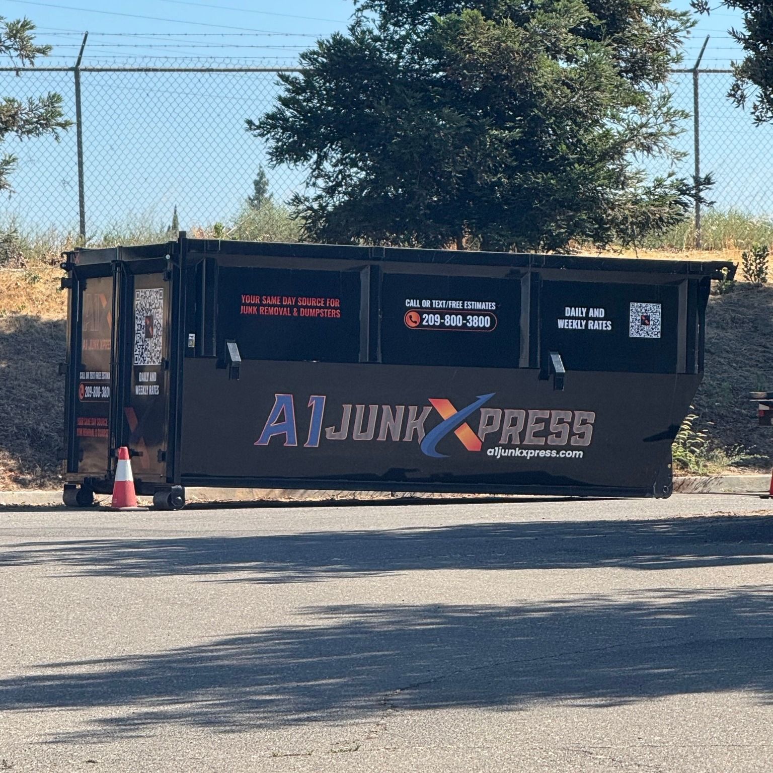 A black dumpster labeled 